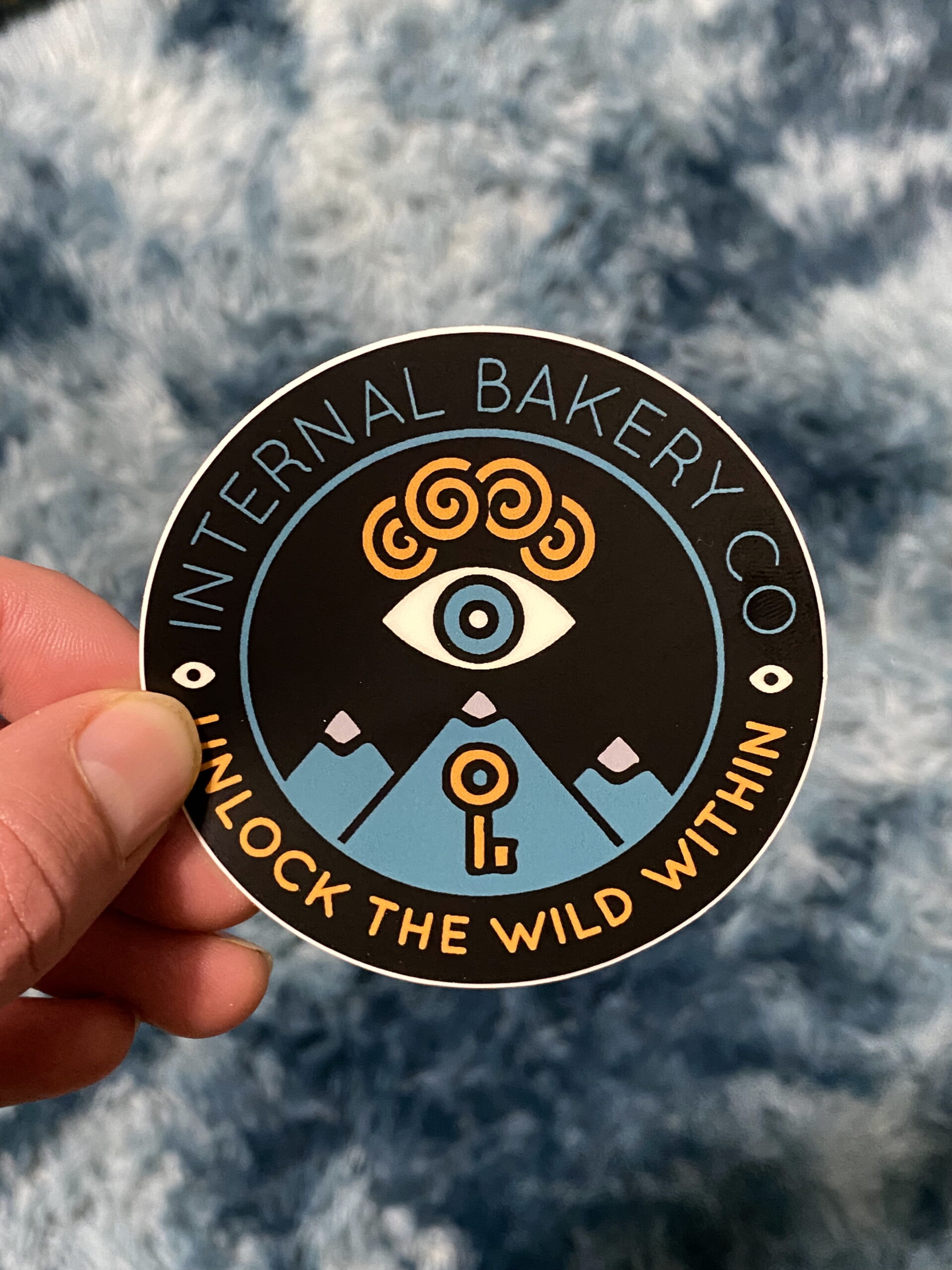 Internal Bakery Logo Sticker (3”) Unlock the Wild Within. This 3-inch sticker features the reimagined Internal Bakery logo — a symbol of imagination, curiosity, and the wild creative spirit that lives inside us all. Hand-drawn and designed in Colorado Springs, this mark represents the heart of our rebrand: Unlock the Wild Within. Stick it anywhere that needs a little spark — your water bottle, laptop, sketchbook, or car window — and let it remind you to keep creating, keep exploring, and keep seeing the world through your own wild lens. Durable, weatherproof, and made to last — just like your imagination.